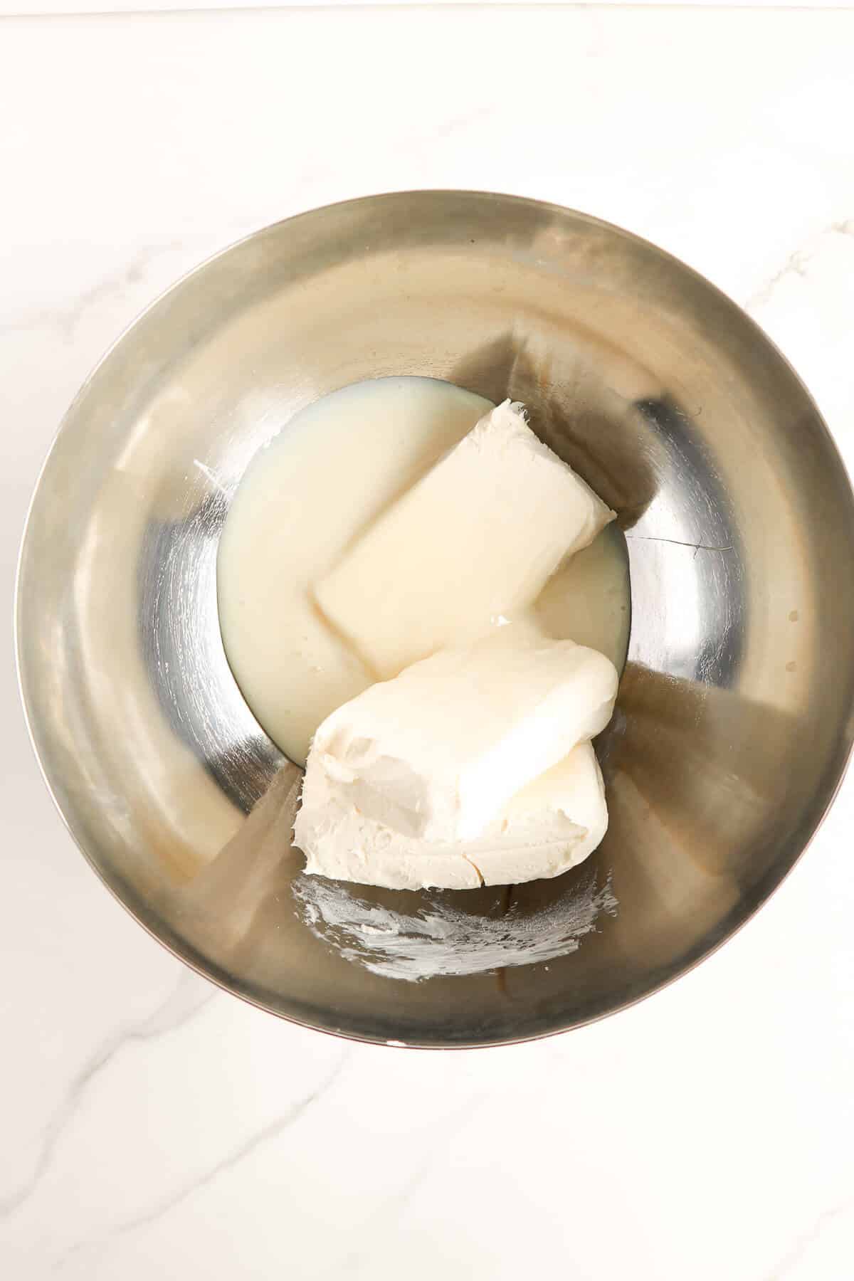 Cream cheese and condensed milk in a mixing bowl