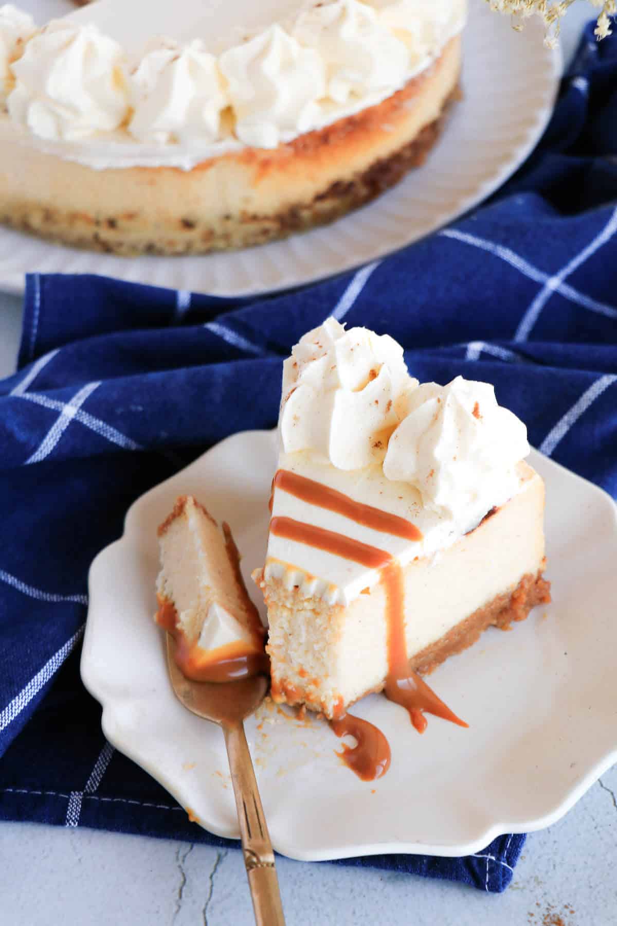 Ponche de crème cheesecake slice with whipped cream and caramel sauce.