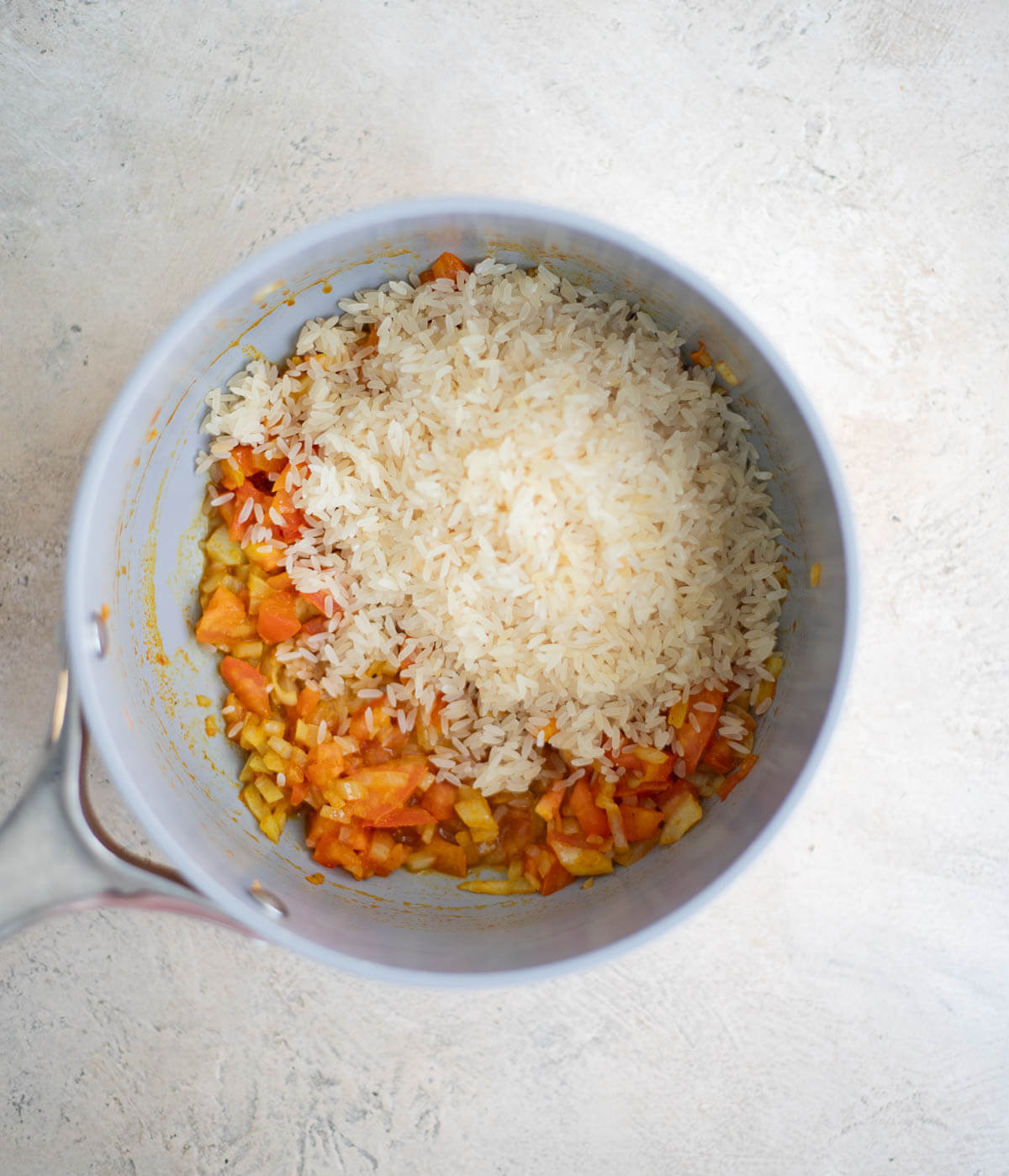 Rinsed parboiled rice added to the cooked curry, onion, and tomato mixture