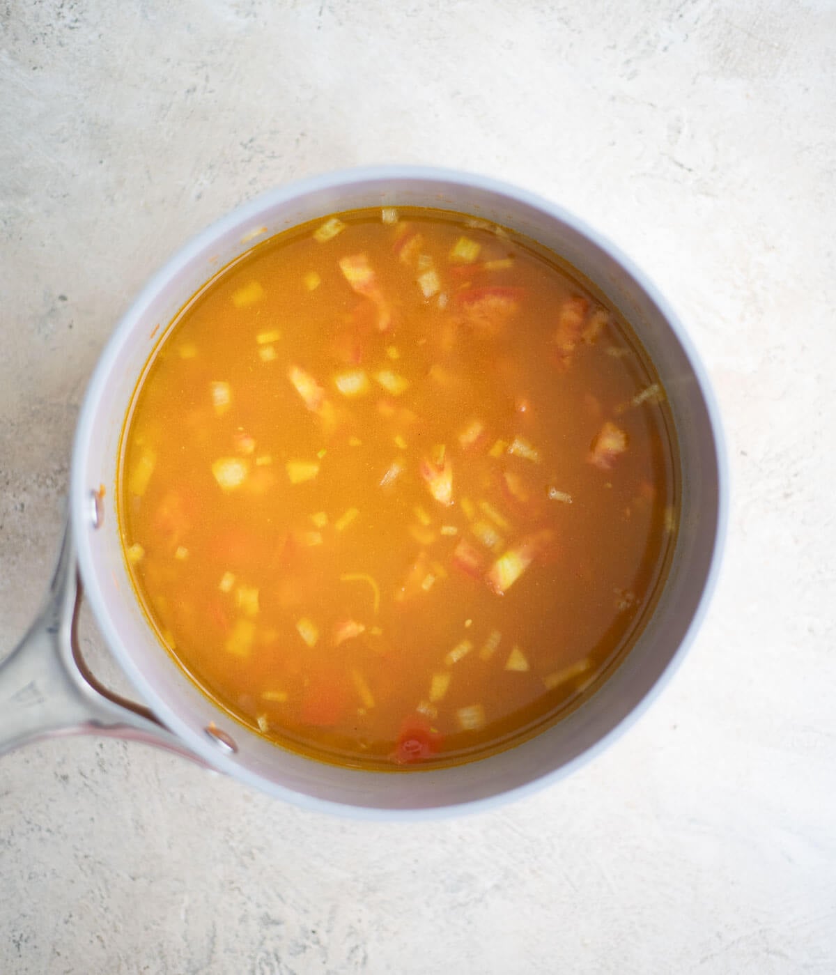 Parboiled rice, tomato, and curry seasonings covered with water before simmering