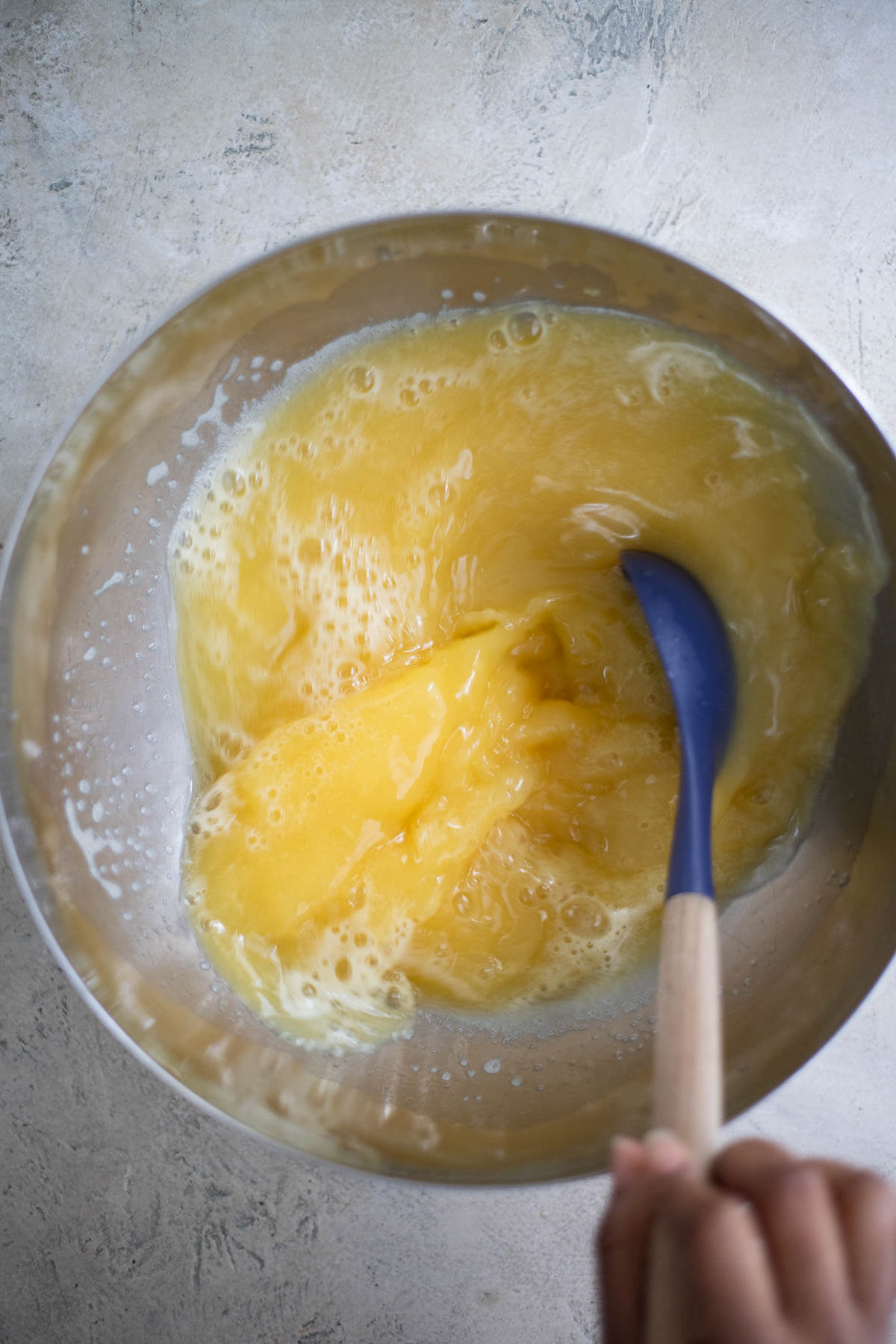 Stirring freshly strained star fruit juice in a mixing bowl after adding the flavorings.