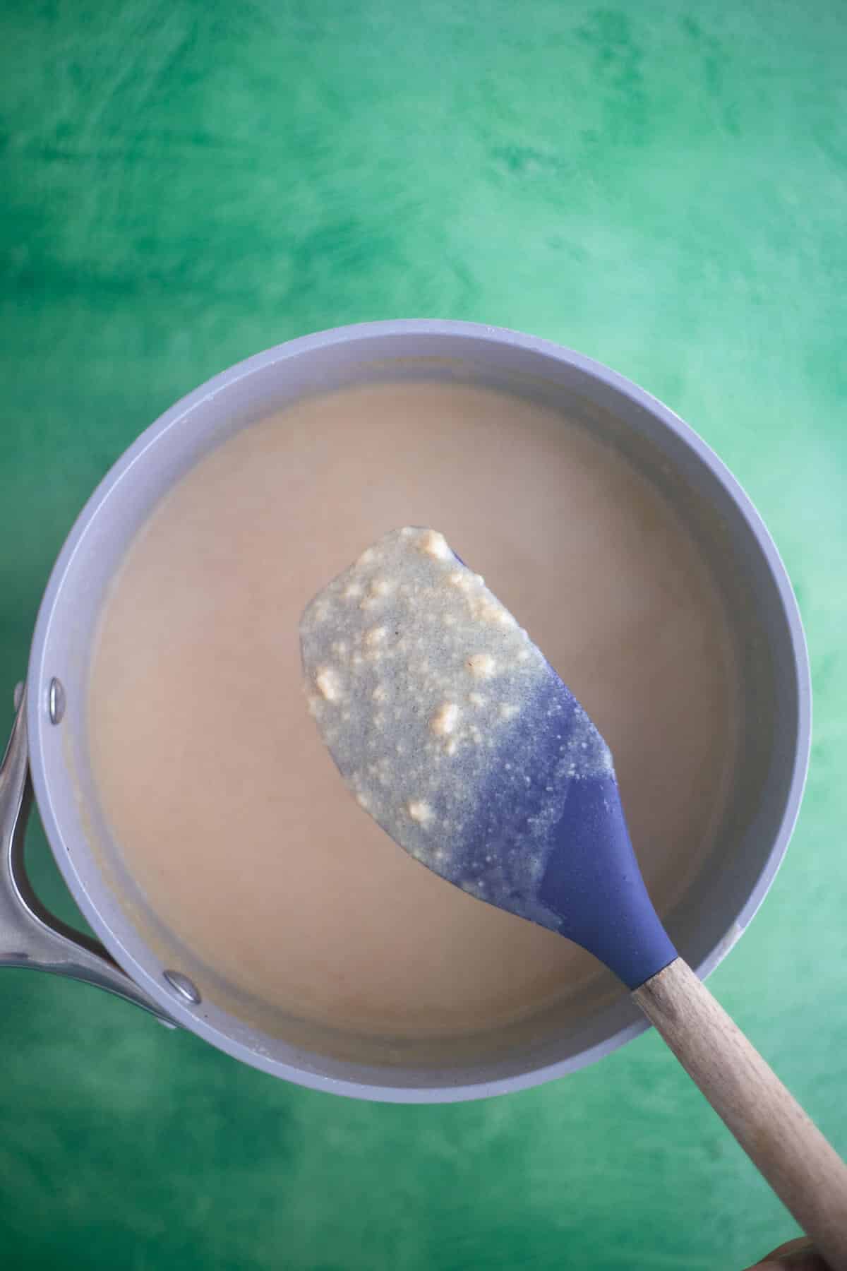 Thickened Ponche de Crème custard coating a spoon after cooking on the stovetop.