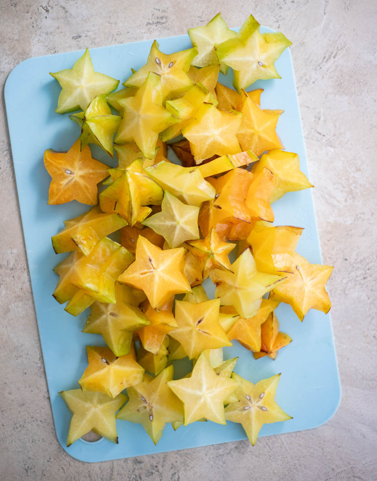 Sliced ripe star fruit showing its star shape, skin, and seeds before blending into juice.
