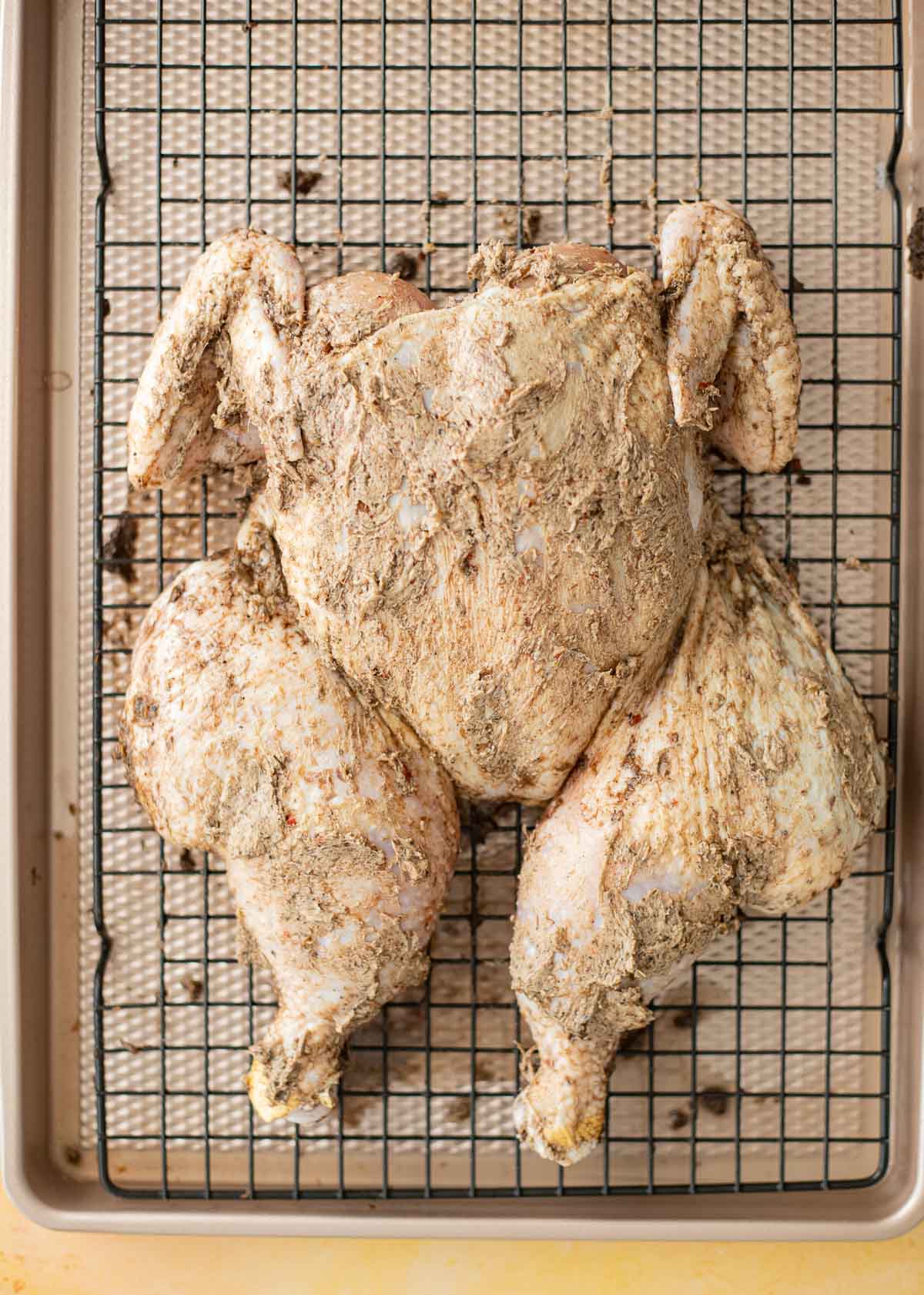 Spatchcocked chicken coated with jerk butter before roasting in the oven.