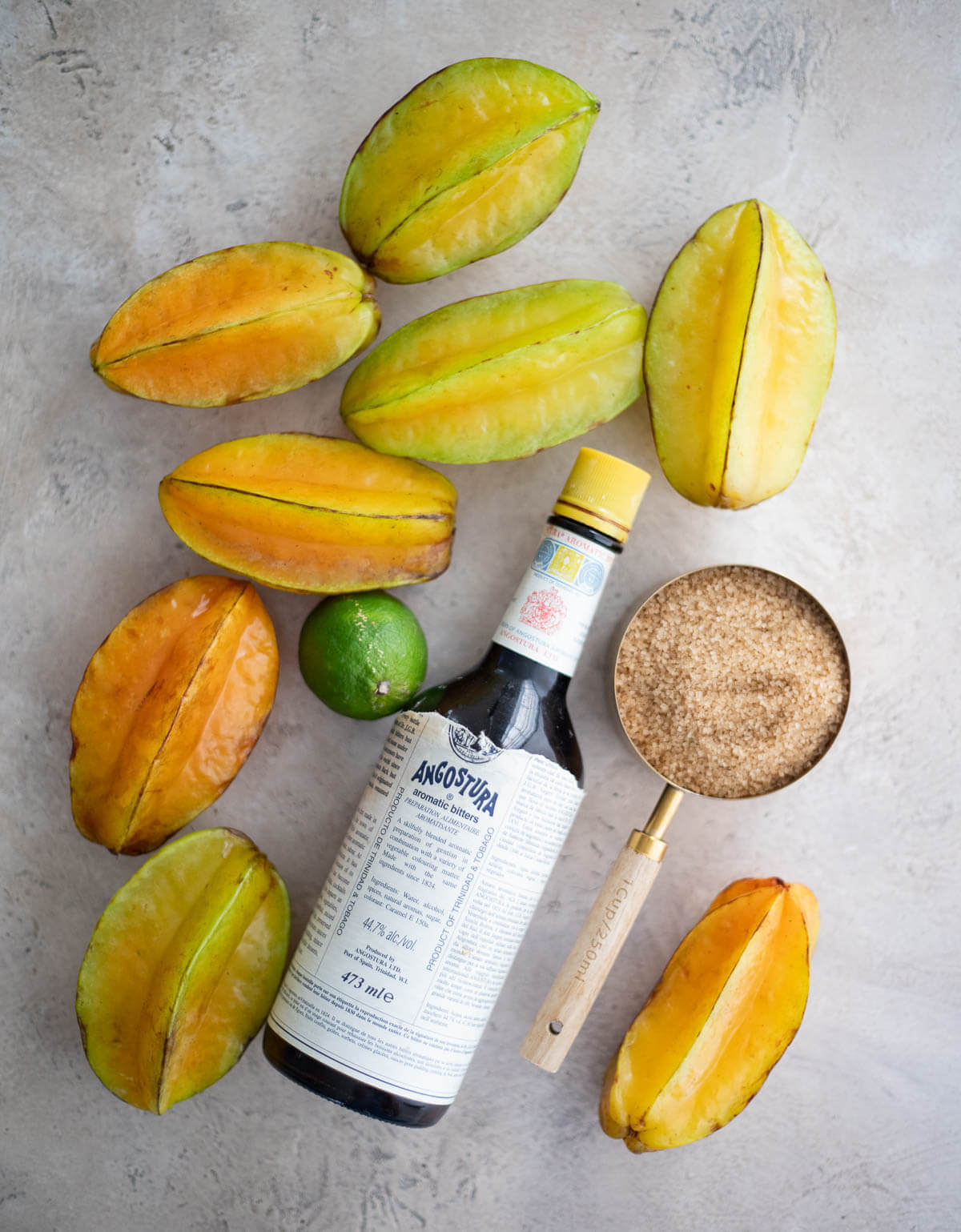 Whole ripe star fruit in shades of green and yellow with brown sugar, lime, and Angostura bitters.